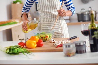 Gülümseyen genç kadın taze salata hazırlıyor.