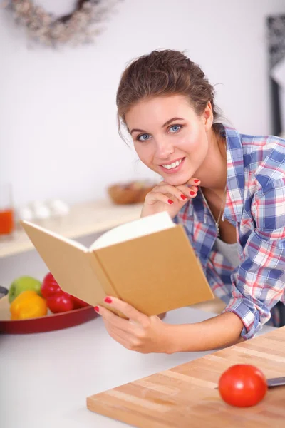 Jovem mulher lendo livro de receitas na cozinha, à procura de receita — Fotografia de Stock