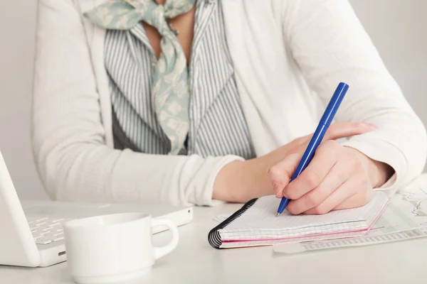 Una donna alla scrivania scrive su un foglio, isolata su bianco — Foto Stock