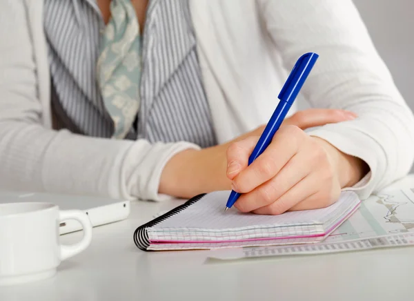 Una donna alla scrivania scrive su un foglio, isolata su bianco — Foto Stock