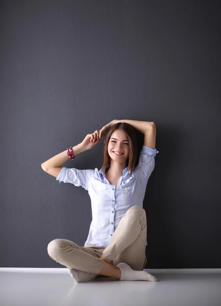 Mujer joven sentada en el suelo cerca de la pared oscura —  Fotos de Stock