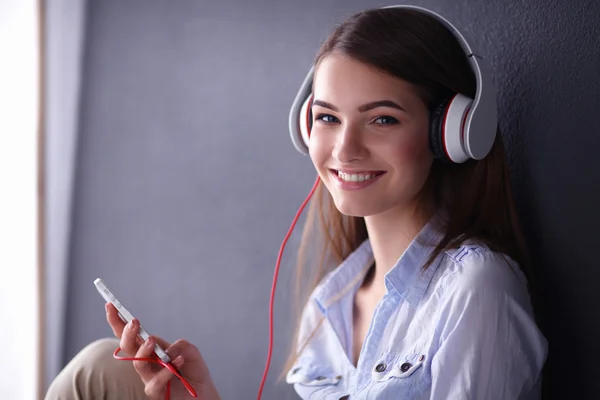 Chica sonriente con auriculares sentados en el suelo — Foto de Stock