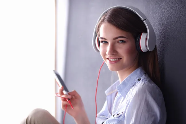 Chica sonriente con auriculares sentados en el suelo — Foto de Stock