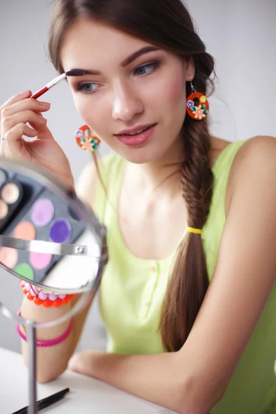 Joven hermosa mujer haciendo maquillaje cerca del espejo —  Fotos de Stock