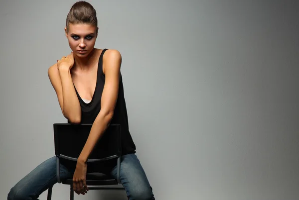 Beautiful woman  sitting  a chair, isolated on gray background — Stock Photo, Image