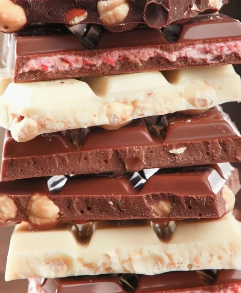 Stapel von Schokoladenstücken auf schwarzem Hintergrund — Stockfoto