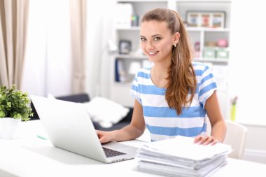 Masasında ve bilgisayarında evrakları olan bir kadın.