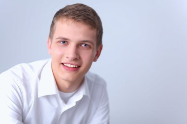 Gri arka plan üzerinde izole gülümseyen genç adam portresi