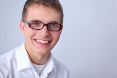 Gri arka plan üzerinde izole gülümseyen genç adam portresi