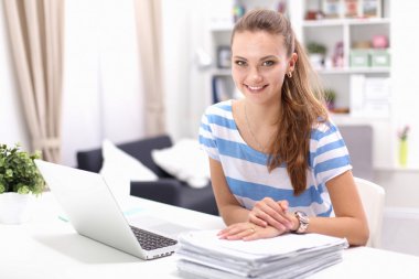 Elinde evrakları olan kadın masanın üstünde oturuyor.