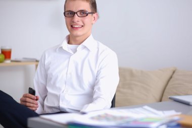 Genç işadamı ofiste çalışıyor, masada oturuyor.