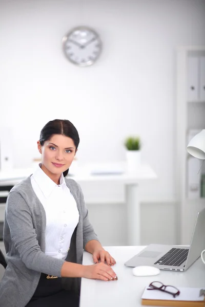 一个带着笔记本电脑坐在办公桌前的女商人的画像 — 图库照片