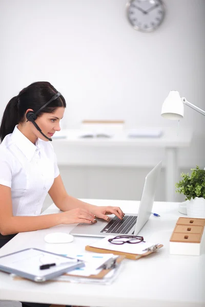 Retrato de mulher de negócios bonita trabalhando em sua mesa com fone de ouvido e laptop — Fotografia de Stock