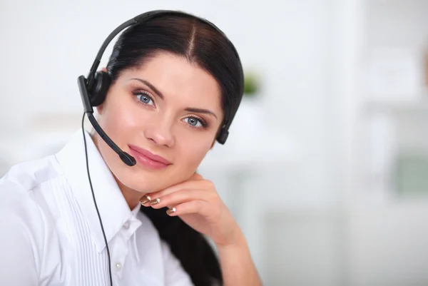 Retrato de mulher de negócios bonita trabalhando em sua mesa com fone de ouvido e laptop — Fotografia de Stock