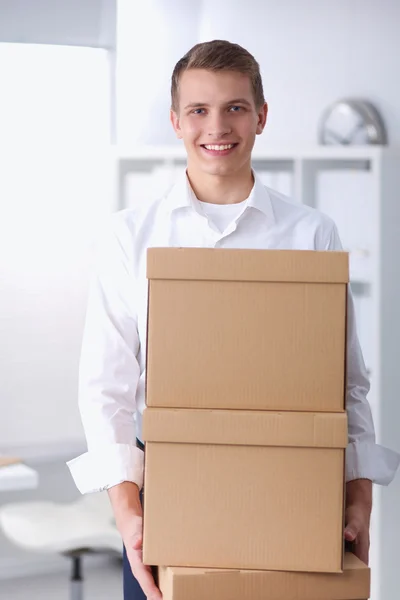 Jonge Man met een stapel van kartonnen dozen permanent in office — Stockfoto