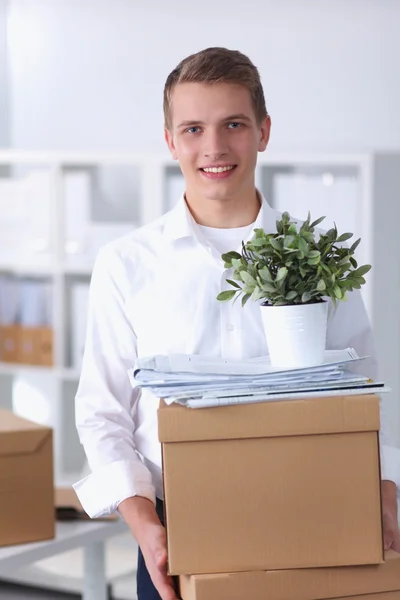 Junger Mann mit einem Stapel Pappkartons im Büro — Stockfoto