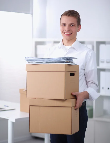 Young Man holding a stack of cardboard boxes standing in office — Stock Photo, Image