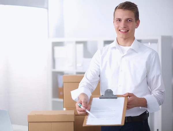 Delivery man with  parcel and a tablet standing in office — Stock Photo, Image