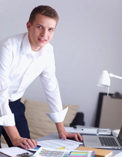 Young businessman working in office, standing near desk — Stock Photo, Image