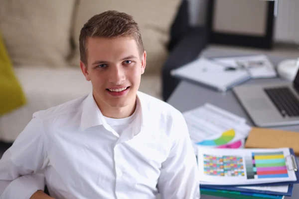 Smiling businessman with folder sitting in the office — Stock Photo, Image