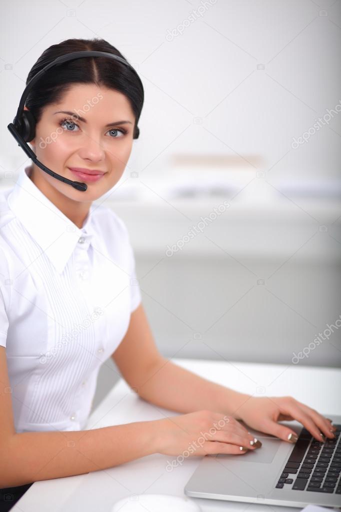 Portrait of beautiful businesswoman working at her desk with headset and laptop