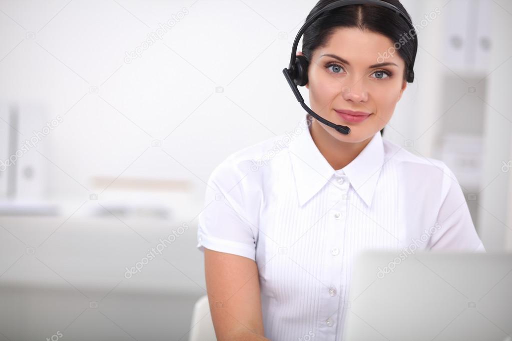 Portrait of beautiful businesswoman working at her desk with headset and laptop