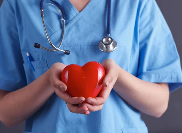 Médico con estetoscopio que sostiene el corazón, aislado sobre fondo gris — Foto de Stock