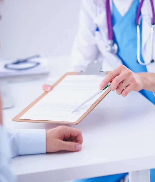 Doktor erkek hasta dosyasına, ofisinde kâğıt olan bir dosya veriyor.