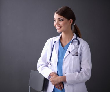 Beautiful female doctor standing near stool isolated grey background clipart