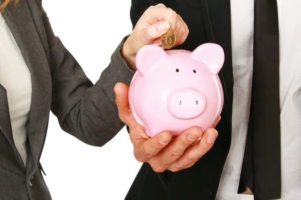 A businesswoman and man putting a coin into a piggy bank isolated on white background — Stock Photo, Image