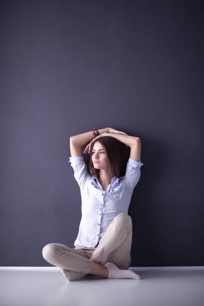 Jeune femme assise sur le sol près du mur sombre — Photo