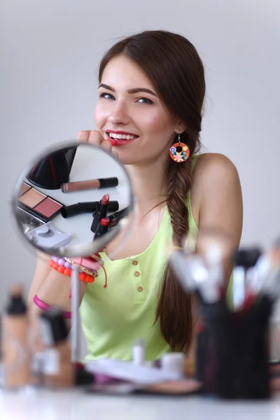 Joven hermosa mujer haciendo maquillaje cerca del espejo — Foto de Stock