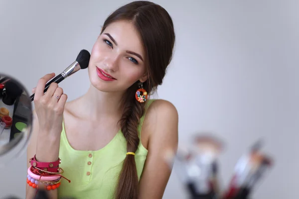 Joven hermosa mujer haciendo maquillaje cerca del espejo — Foto de Stock