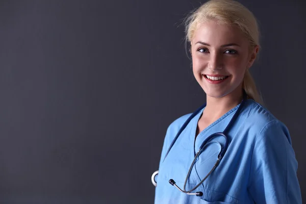 Молодая женщина-врач со стетоскопом изолирована на сером — стоковое фото