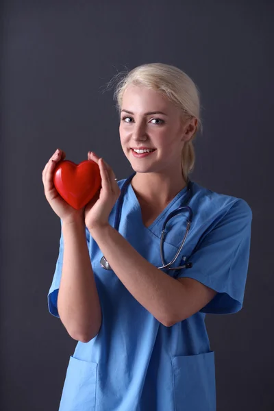 Doctor with stethoscope holding heart, isolated on grey background — Stock Photo, Image