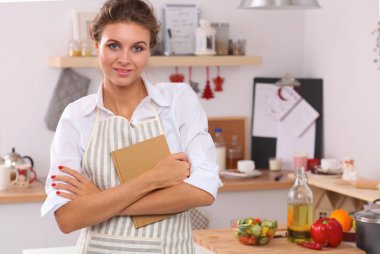 Mutfakta gülümseyen genç bir kadın, Noel arkaplanında soyutlanmış.