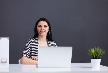 Masasında kulaklığı ve laptopuyla çalışan güzel bir iş kadını.