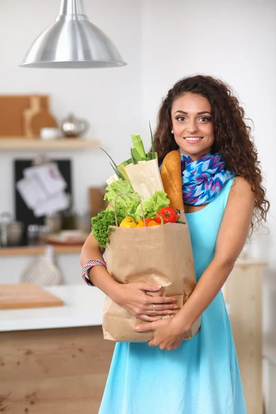 Young woman holding grocery shopping bag with vegetables Standing in the kitchen. — Stock Photo, Image