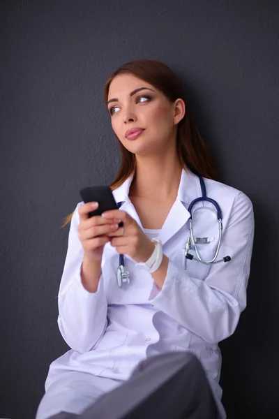 若い女性の医者はあなたの携帯電話で床に座って — ストック写真
