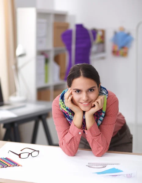 Młoda atrakcyjna projektantka mody pracująca w biurze, rysująca podczas rozmowy na telefonie komórkowym — Zdjęcie stockowe