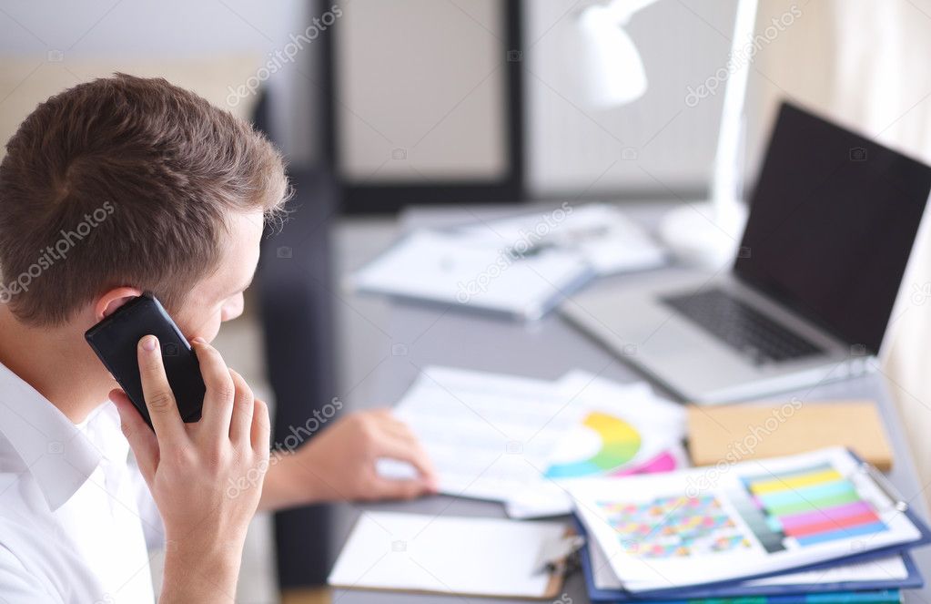 Young businessman working in office, sitting at desk