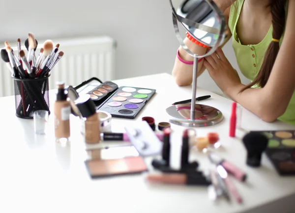 Mladá krásná žena, takže make-up zrcadla, sedící u stolu — Stock fotografie