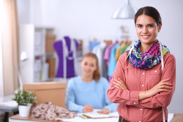 Junge attraktive Modedesignerin arbeitet am Schreibtisch und zeichnet, während sie mit dem Handy spricht — Stockfoto