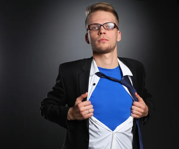 Joven hombre de negocios actuando como un súper héroe y rasgando su camisa, aislado sobre un fondo gris —  Fotos de Stock