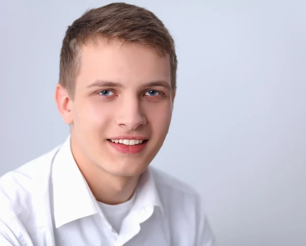 Porträtt av ung man leende sitter på grå bakgrund — Stockfoto