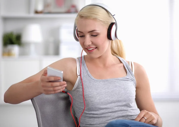 Young beautiful woman at home sitting on sofa and listening music — Stock Photo, Image