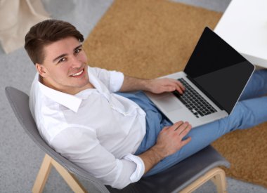 Genç işadamı ofiste çalışıyor, masada oturuyor.