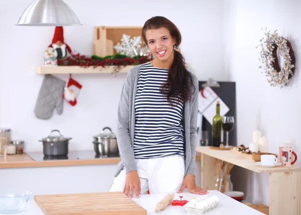 Smilende ung kvinne på kjøkkenet, i julen bakgrunn – stockfoto