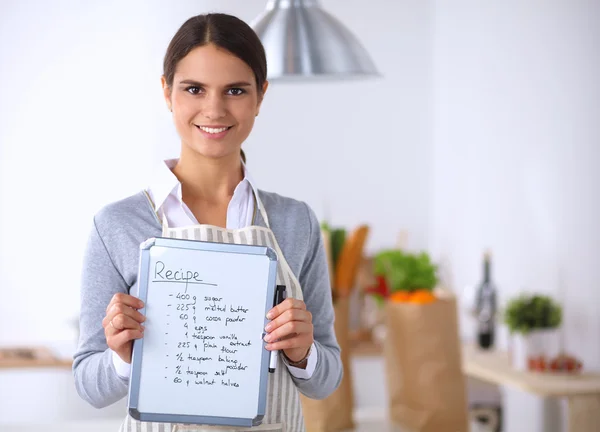 Donna in cucina a casa, in piedi vicino alla scrivania con cartella — Foto Stock