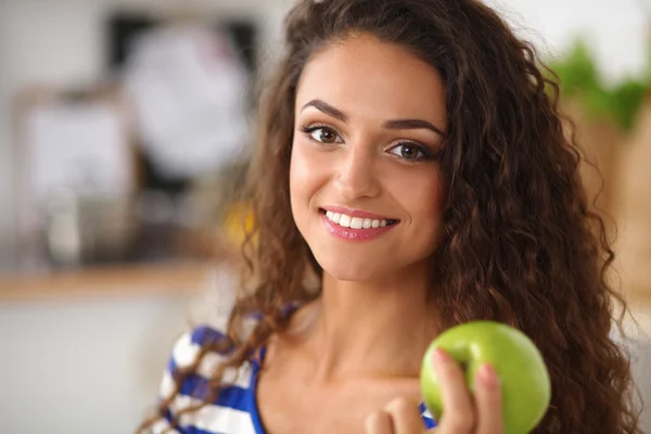 幸せな若い女性食べるリンゴ上のキッチン — ストック写真